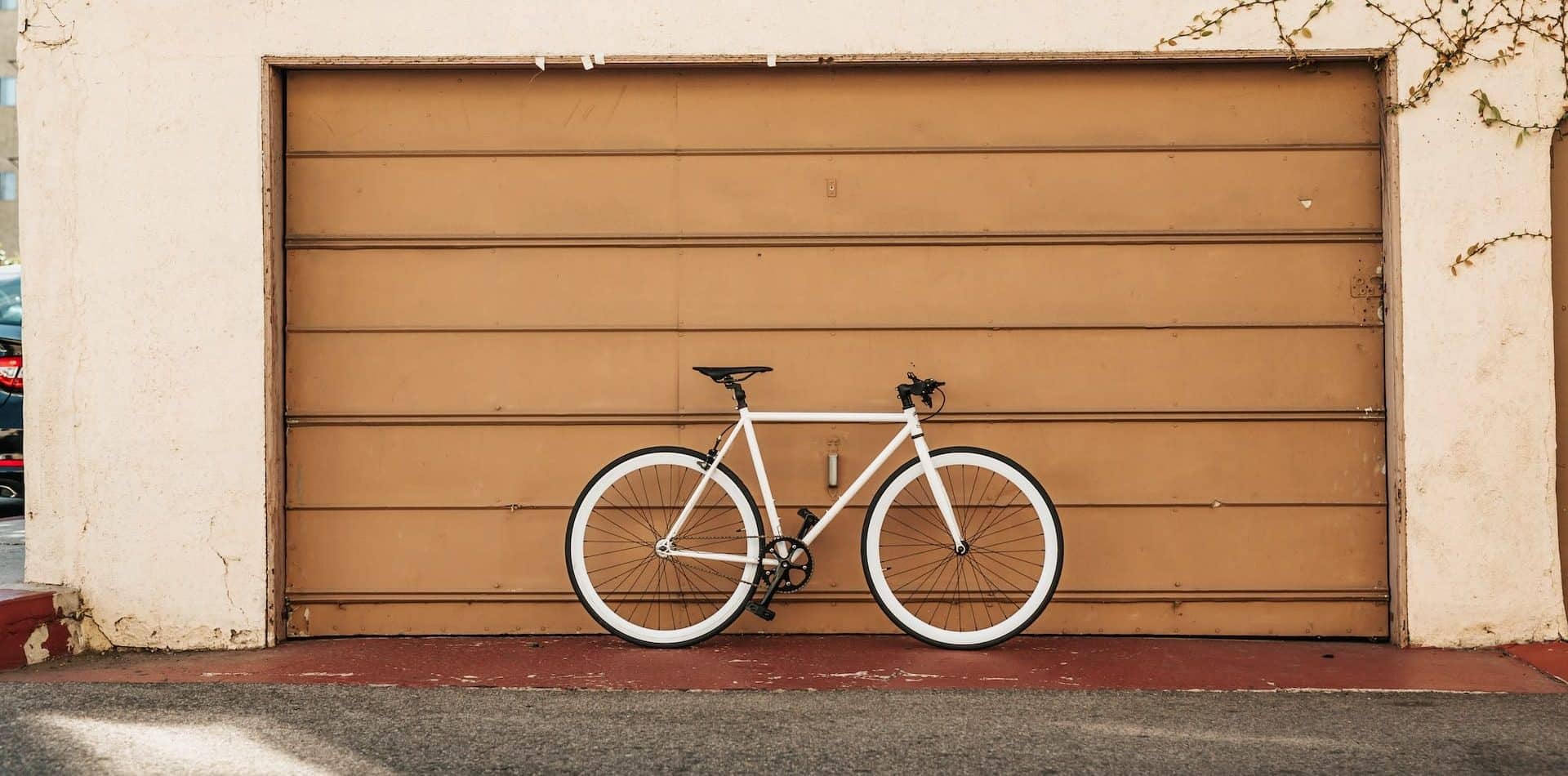 Fahrrad Garage, Tyler Nix on Unsplash Weißes Fahrrad vor brauner Garage