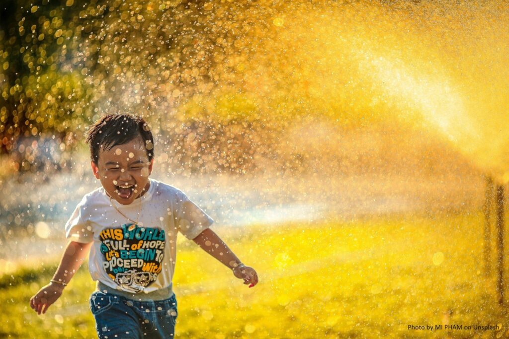 Kind läuft durch eine Gartendusche