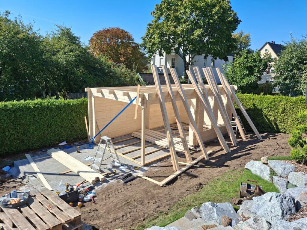 Teilweise aufgebautes Gartenhaus mit stehenden Holzlatten