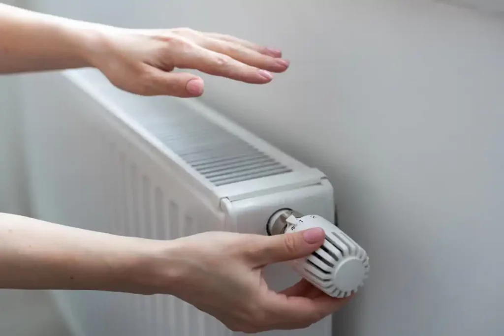 frau stellt temperatur am heizkoerper ein
