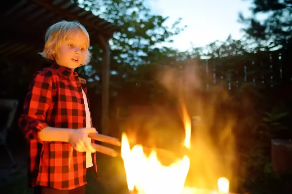 junge am lagerfeuer an einem sommerabend