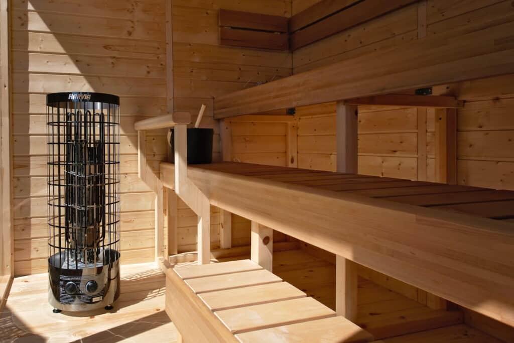 Innenansicht einer Holzsauna mit Bänken und Saunaofen