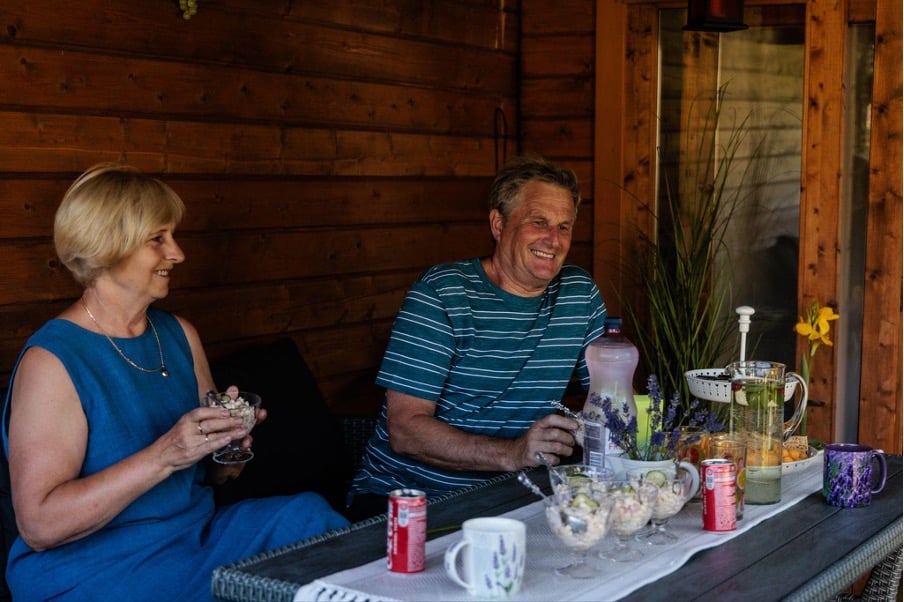 Älteres Ehepaar lacht gemeinsam am Gartentisch