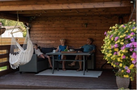 Älteres Paar mit Enkelkind auf der Terrasse des Gartenhauses