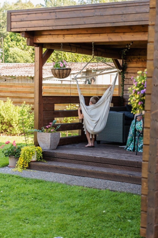 Kind im Hängesessel auf der Veranda des Gartenhauses