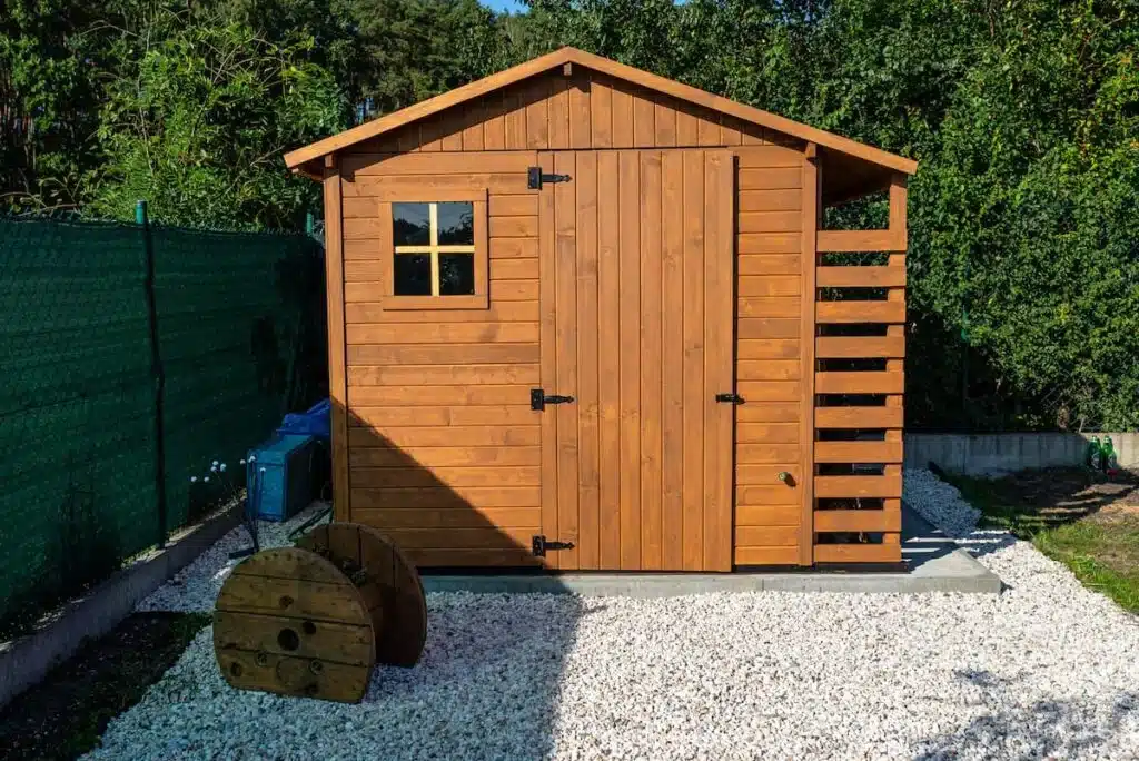 Ein Gartenhaus aus Holz auf einem Betonfundament in einem Garten.